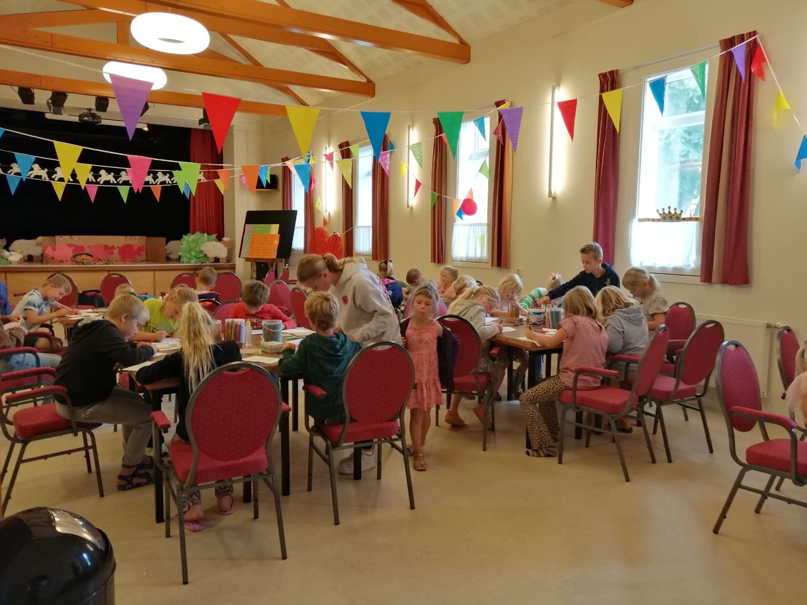 Kinderen knutselen aan tafels in Dorpshuis De Stoek